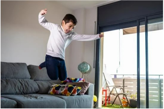 a boy happily jumping off a couch