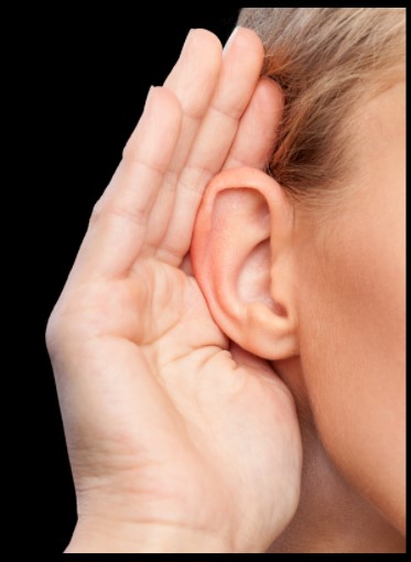 A person holding a hand to an ear to listen