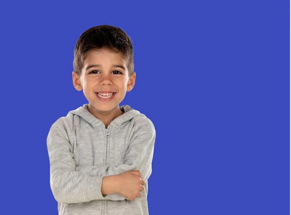 Image of a young smiling boy with arms folded and eyes on us is an example of an engaged dyslexic student.